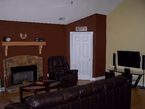 Cozy Sunshine Residential Care living room with a fireplace, leather seating, and a TV.