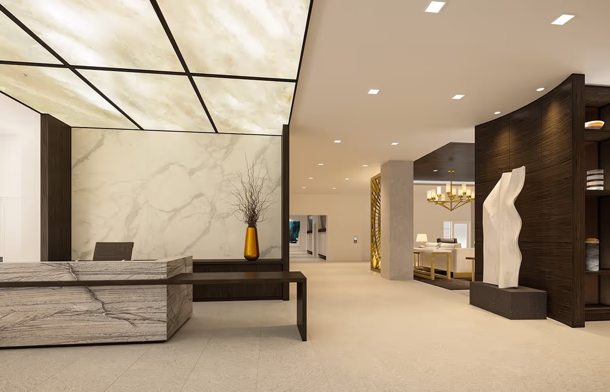 Modern reception area with a marble front desk and a dark wooden bench attached. Behind the desk is a wall with a marble pattern and a tall golden vase holding decorative branches. The ceiling above the desk has illuminated panels. To the right, there is a dark wooden partition with a white abstract sculpture on a pedestal and a glimpse of a seating area with a chandelier and furniture in the background.