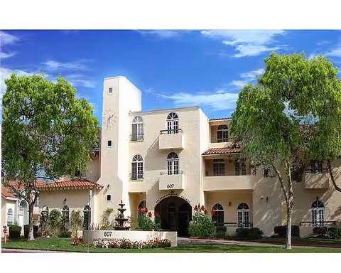 Exterior view of Arcadia Retirement Village building with arches, trees, and a fountain.