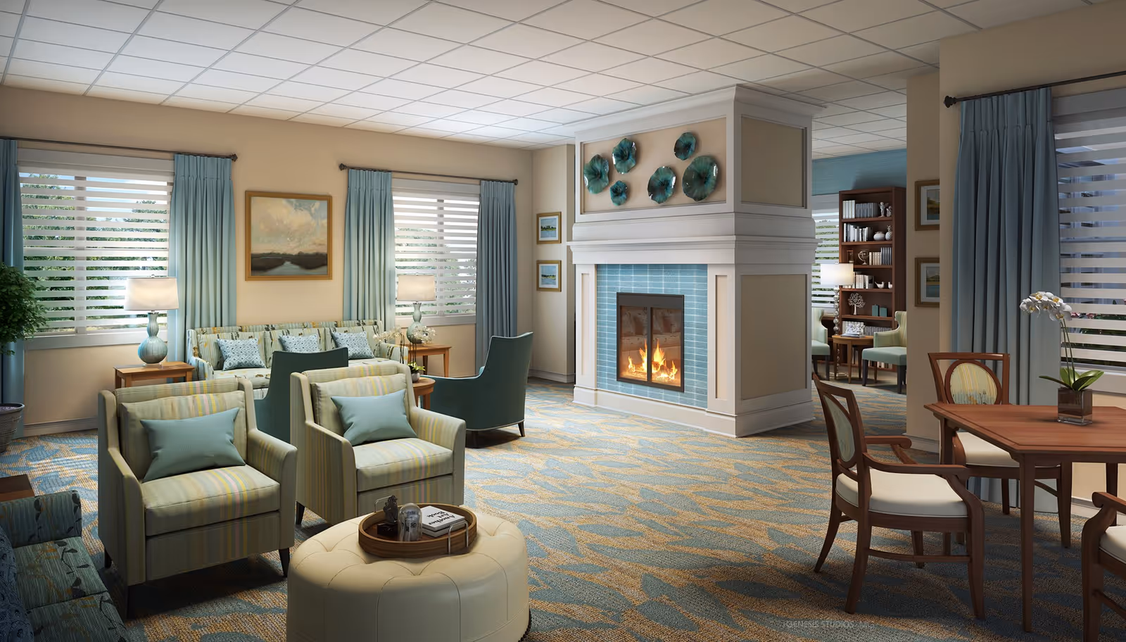 A cozy and well-lit living room in an assisted living community featuring a central fireplace with blue tiles and decorative wall art above it. The room has multiple seating options including armchairs with striped upholstery, a sofa with cushions, and wooden chairs around a small table. Large windows with light blue curtains allow natural light to fill the space, and there are table lamps and a potted plant adding to the warm ambiance.