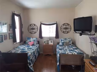 Shared bedroom with two twin beds, dresser, and wall-mounted TV.