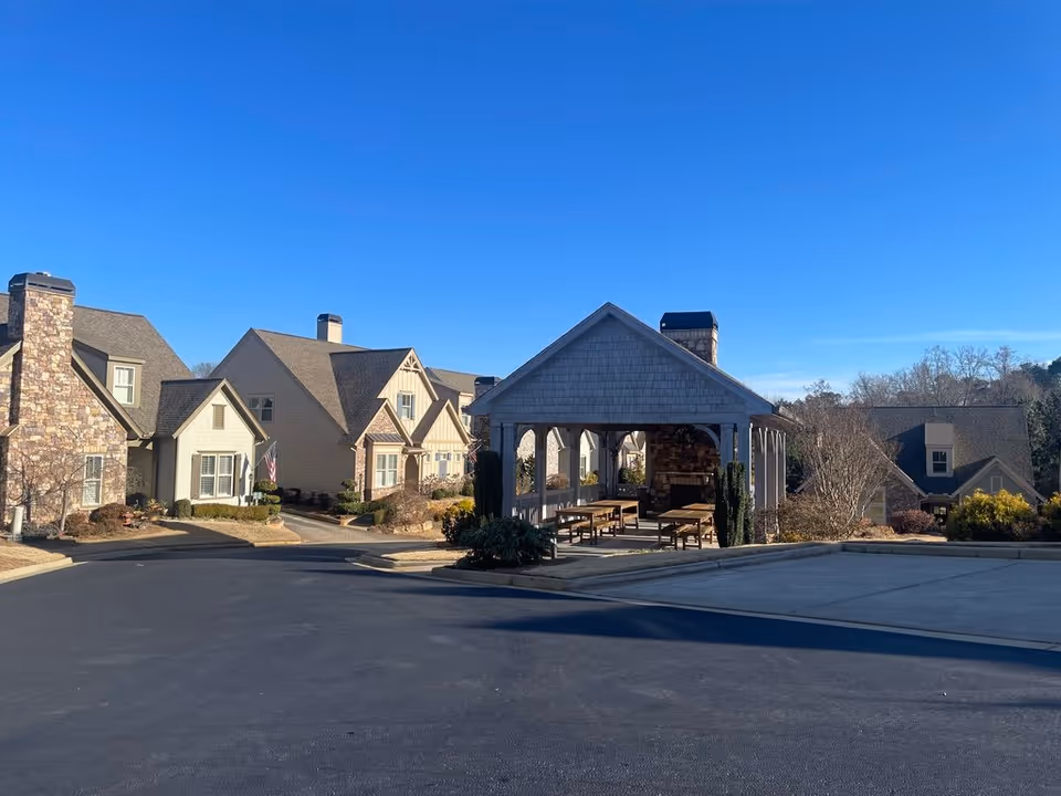 A covered outdoor pavilion and surrounding residential buildings in a senior living community under a clear blue sky.