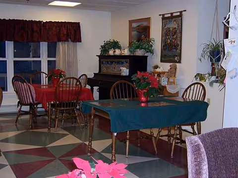 Interior dining area with tables, chairs, potted plants, and a piano.