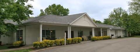 Single-story facility exterior with a covered front entrance and manicured shrubs.