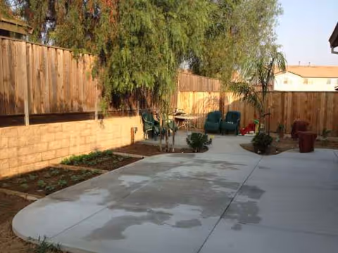 An outdoor patio with seating, planters, and a wooden fence surrounding the area.