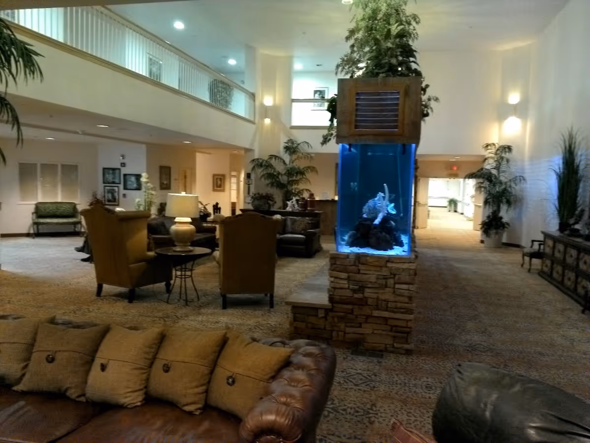Spacious two-story lobby with seating, plants, and a central illuminated aquarium.