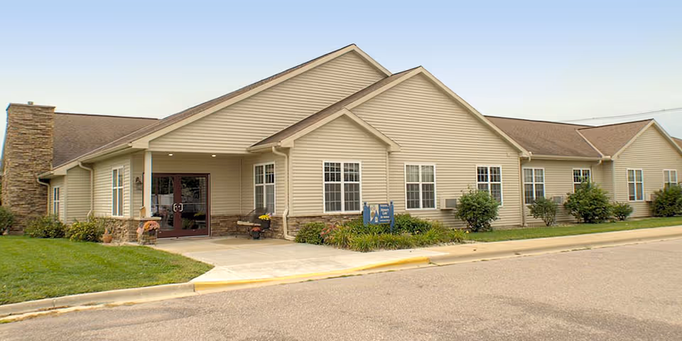 Single-story beige senior living building with covered entrance and manicured landscaping along the curb