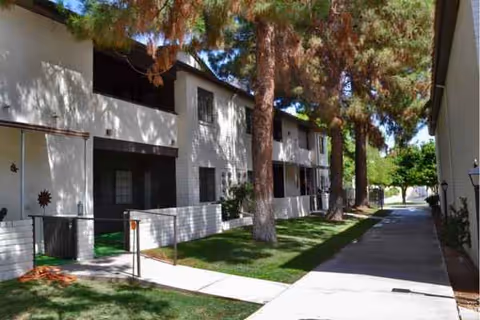 Exterior view of Zen Senior Living facility with white buildings, trees, and a walkway.