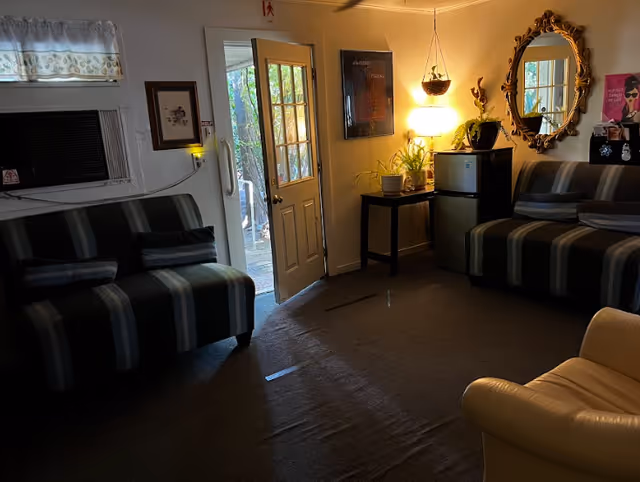 Cozy senior living room with striped sofas, a small table, plants, and a door to outdoors.