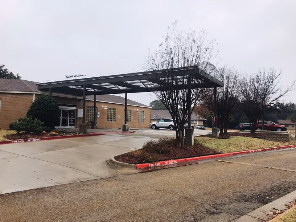 Exterior view of Arlington Villas Rehabilitation and Healthcare Center with a covered entrance and parking.