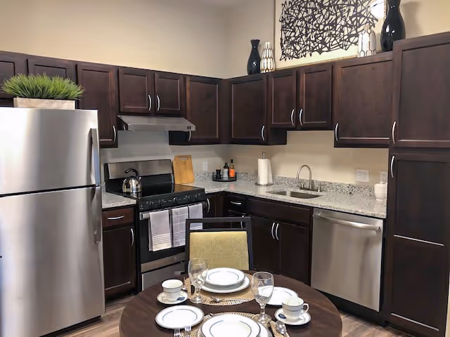 Modern open kitchen with dark wood cabinets, stainless steel appliances and a small round dining table set for four.