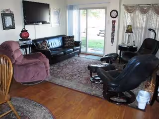 Cozy senior living room with recliners, a black leather sofa, and wall mounted TV
