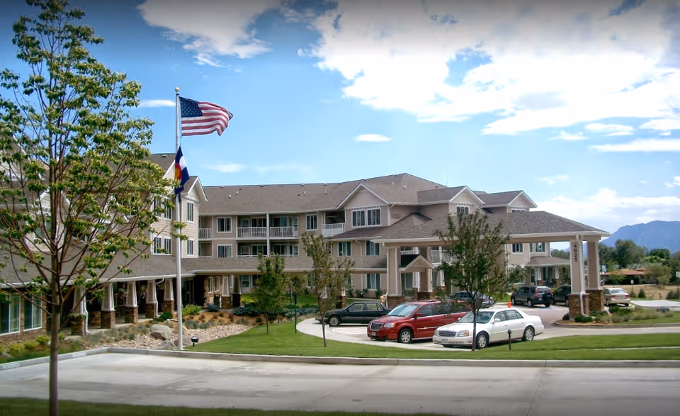 Exterior view of Summit Glen Gracious Retirement Living building with flags and cars.