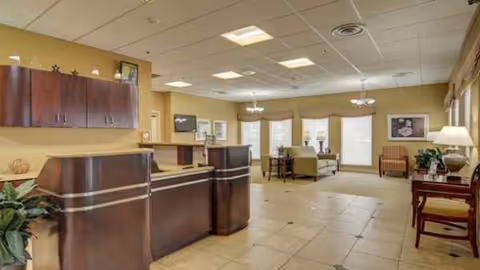 Reception desk and seating area in a bright senior living facility lobby.