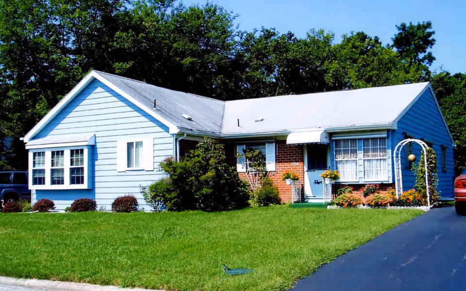 A blue, single-story building with a manicured lawn, shrubs, and a paved driveway in front.