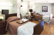A shared patient room with two beds, curtains, and medical equipment in a nursing facility.