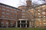 Brick senior living building with a curved entrance portico and leafless trees.