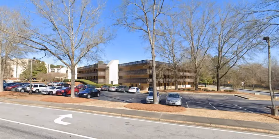 Exterior view of Larry Moore Manor senior living facility with a parking lot and leafless trees.