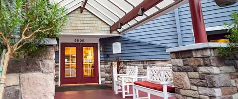 Exterior entrance of a COGIR Senior Living building with blue siding and stone columns.