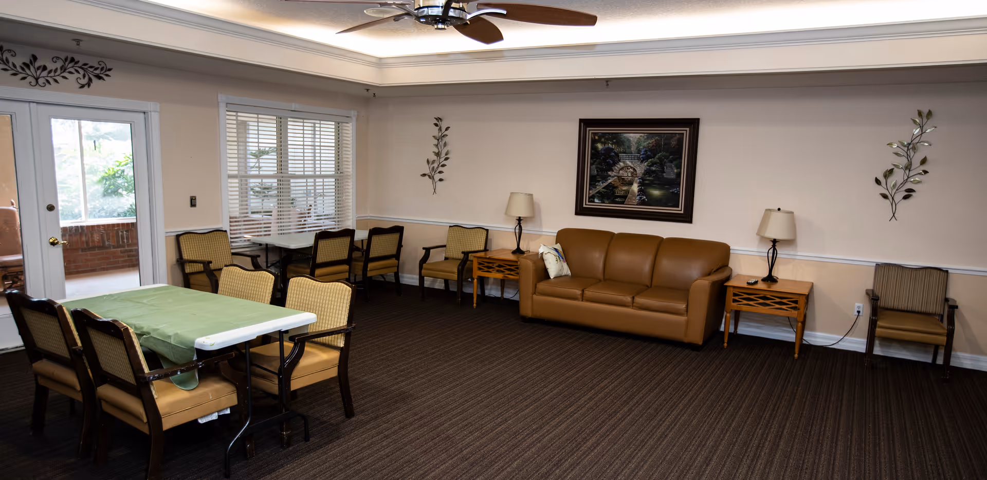 Common lounge area with a brown leather sofa, tables and chairs, lamps, and wall art.