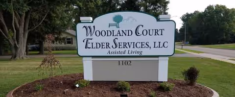 Outdoor sign for Woodland Court Elder Services, LLC Assisted Living on a manicured lawn.