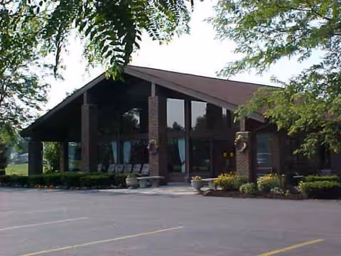Front view of Autumnwood Care Center entrance with brick pillars and glass doors.