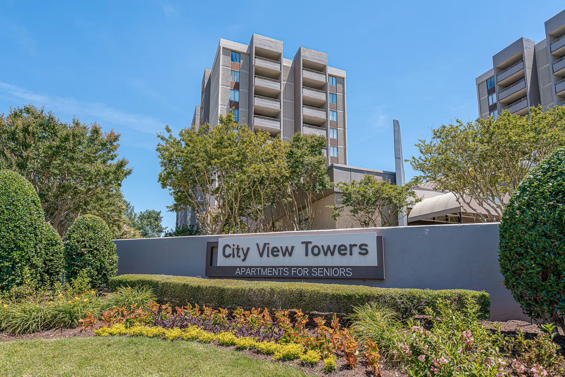 Exterior view of the City View Towers senior apartment building with its entrance sign and landscaped grounds.