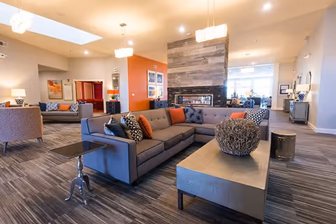 Spacious senior living community lounge with a sectional sofa, coffee table, fireplace, and additional seating areas.