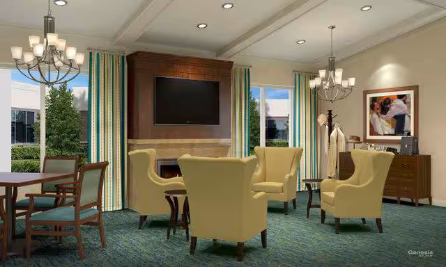 Bright common lounge with yellow armchairs arranged around a fireplace and wall-mounted TV, with a dining table at left.