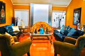 Cozy senior living lounge with orange walls, blue cushions, and a central glass coffee table.