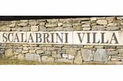 Stone wall with Scalabrini Villa sign marking the facility entrance.
