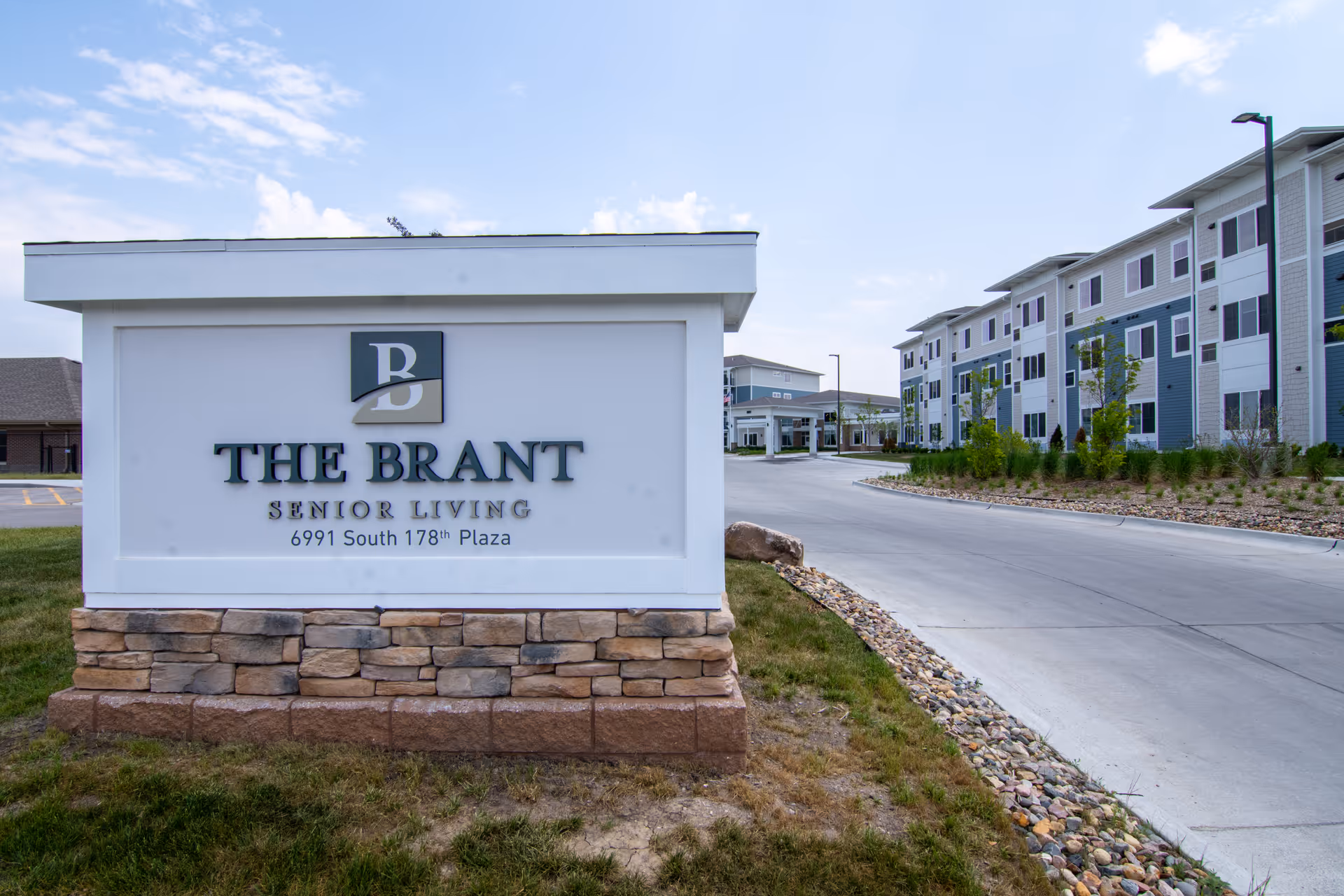 Entrance sign reading 'The Brant Senior Living' with the facility buildings and driveway visible behind it.