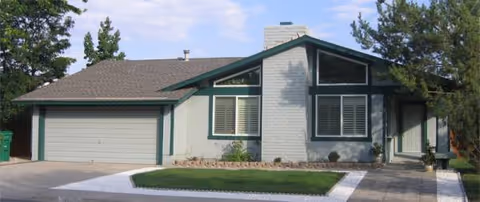 Exterior of a single-story senior living home with a two-car garage and manicured lawn.