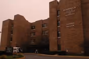 Brick exterior of Peninsula Nursing and Rehabilitation building with signage visible near entrance.