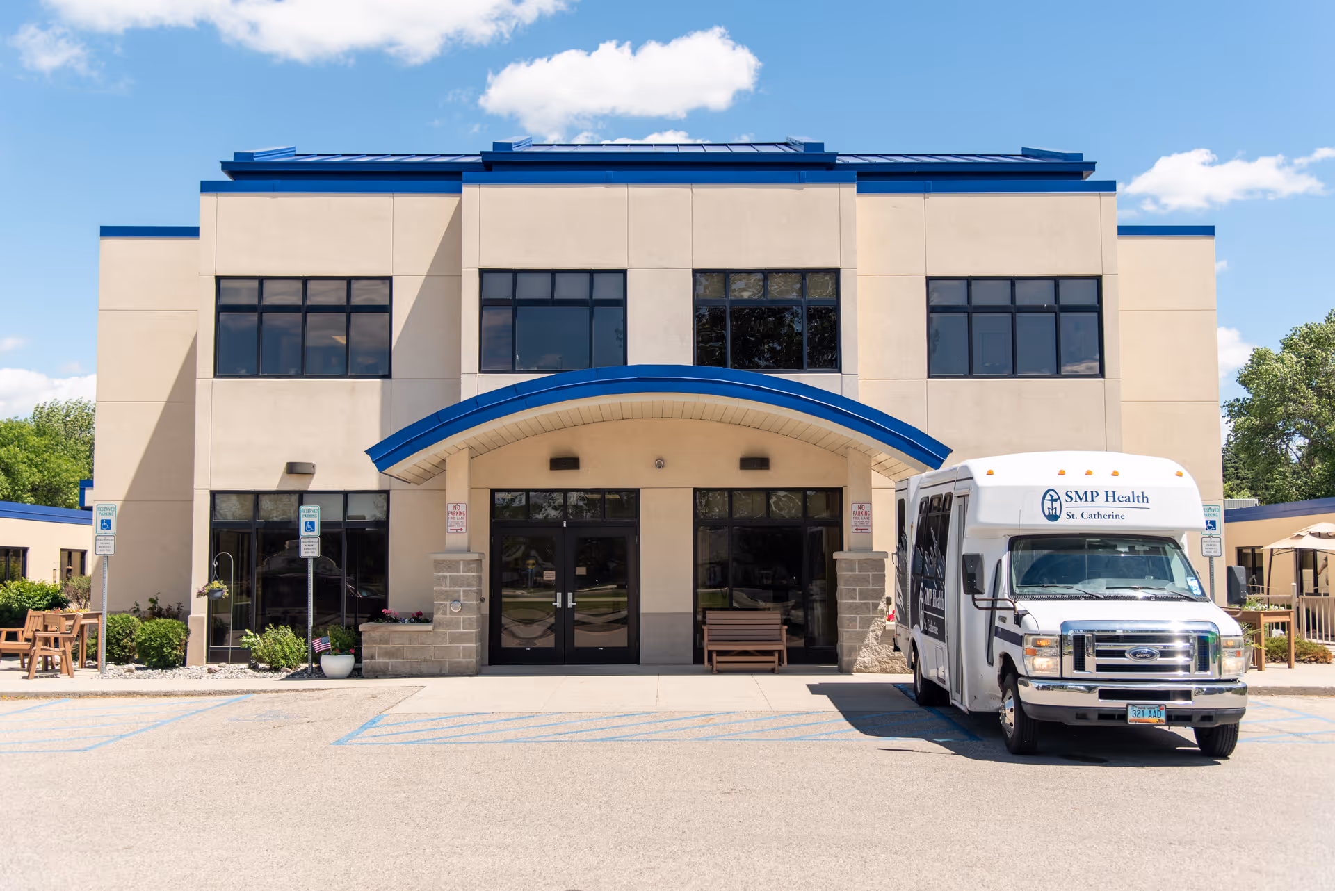 Front exterior of SMP Health - St. Catherine South building with a blue entry canopy and a parked SMP Health shuttle bus.