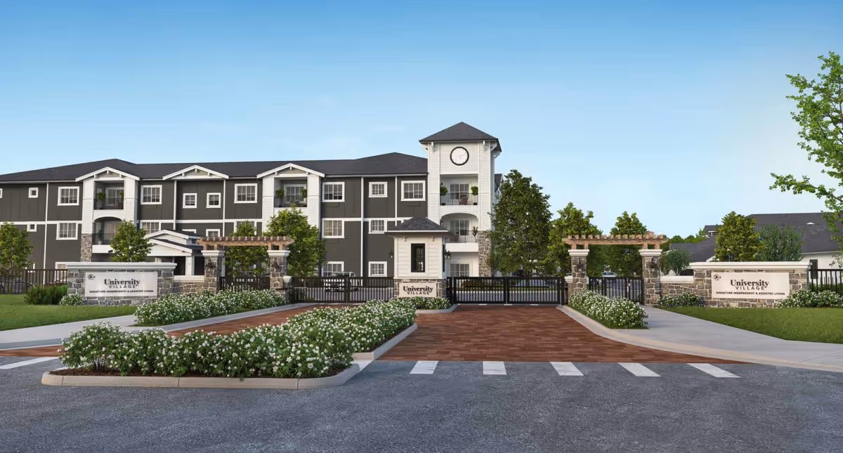 Gated front entrance of a three-story apartment-style senior living building with landscaped medians and entrance signage.