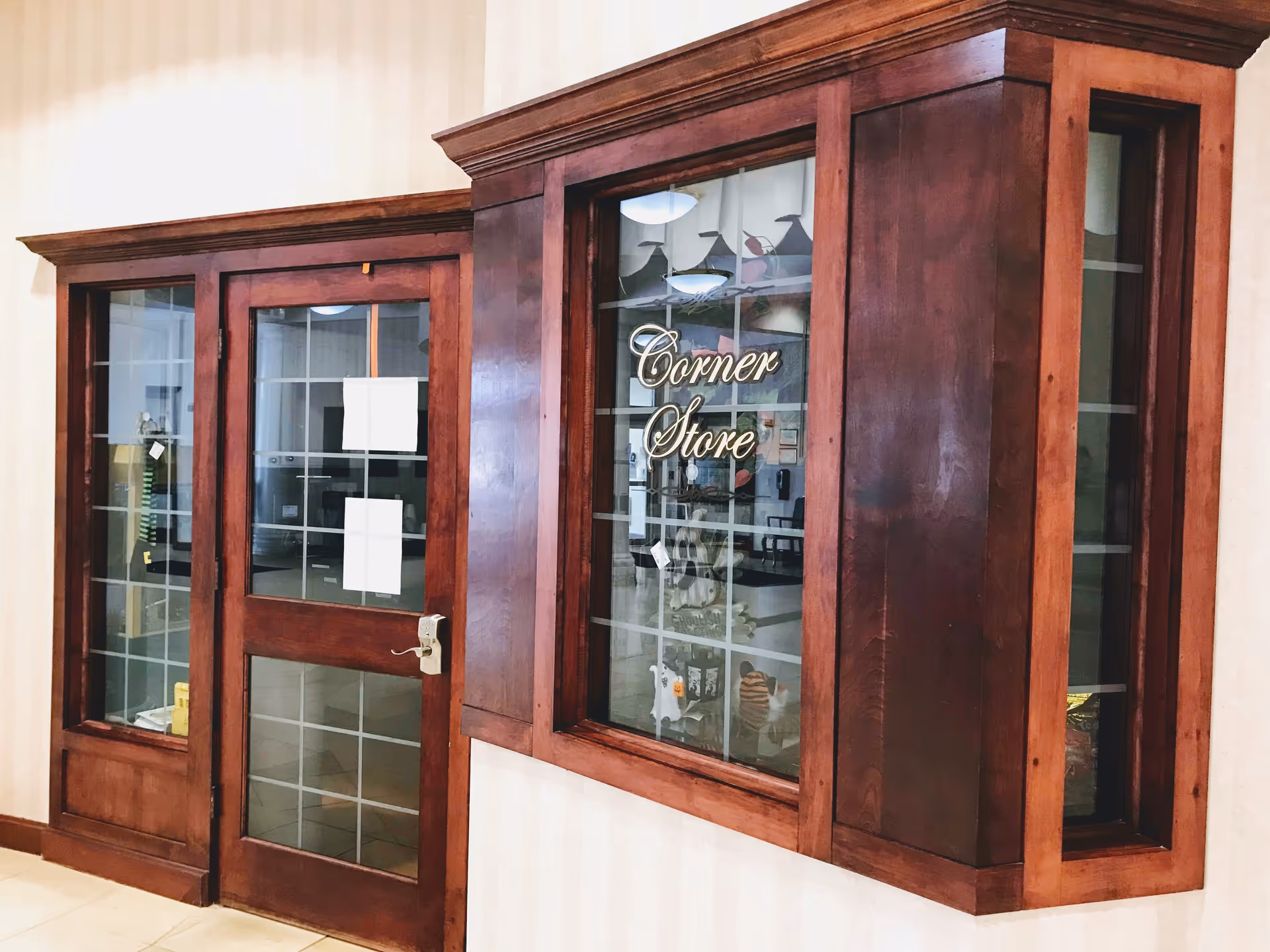 Wood-framed interior window and door with glass panes and 'Corner Store' lettering on the glass.