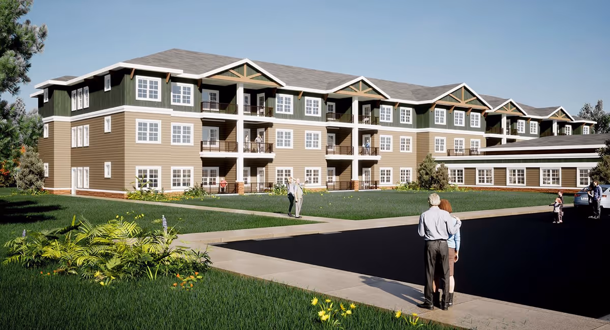 Exterior view of a three-story senior living facility named Wiscasset Green with balconies, green and beige siding, and a landscaped lawn with several people walking and standing around the building.