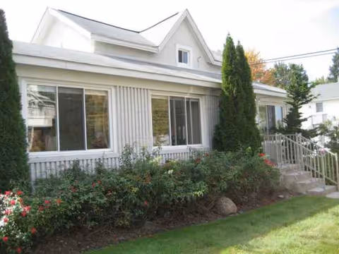 Front exterior of a single-story senior living facility with large windows and landscaping.