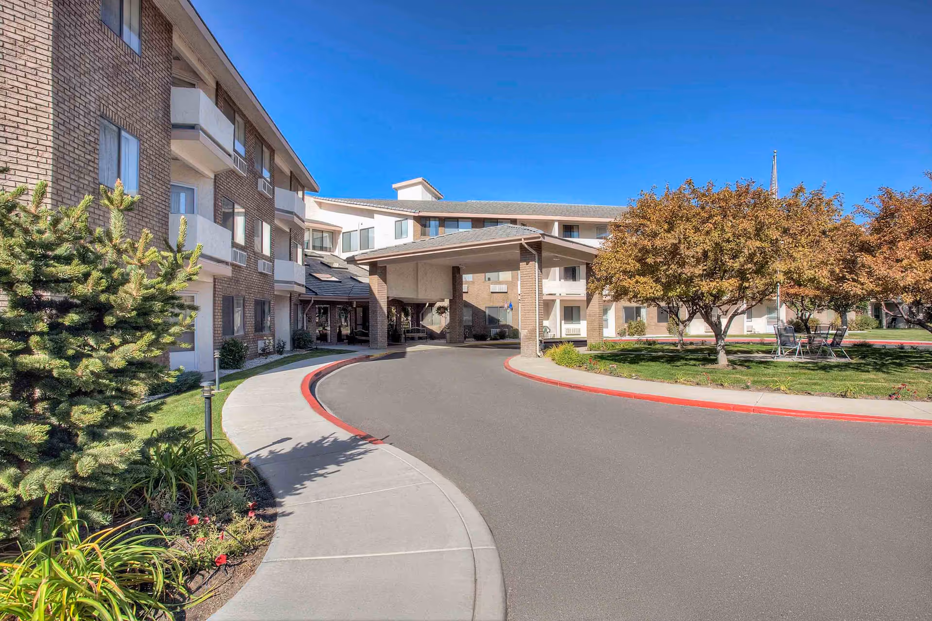 Covered driveway and main entrance of a multi-story senior living building with landscaped grounds and a circular drop-off.