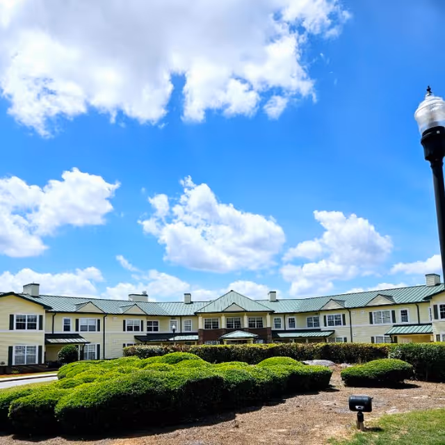 Exterior view of The Haven at Columbus facility with green shrubs and a bright blue sky.