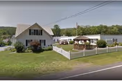 Exterior view of Brookside Nursing Home LLC with white fences, a gazebo, and grassy grounds.
