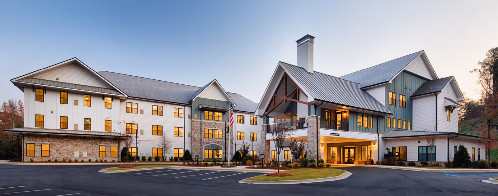 Exterior view of a modern senior living community building with stone accents and a driveway.