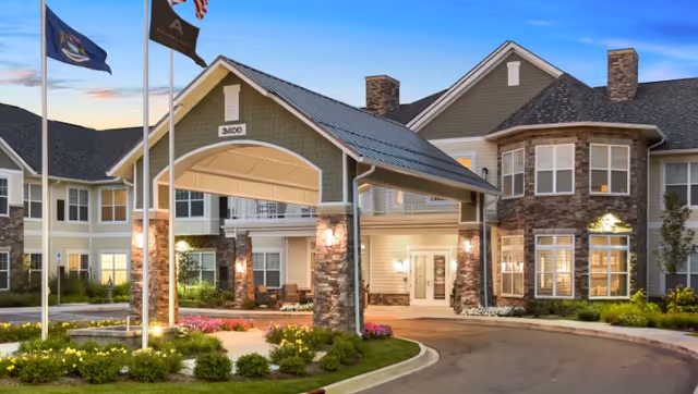 Exterior view of American House Somerset with entrance canopy, stone columns, and flagpoles.