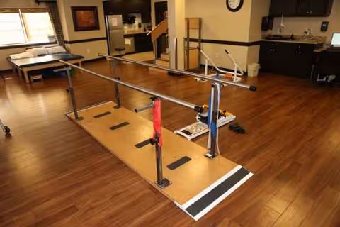 Rehabilitation gym with parallel bars and therapy equipment in a treatment room.