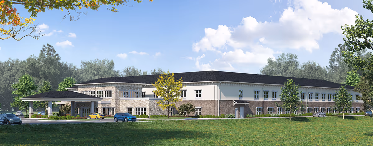 Exterior view of a large senior living facility with a covered entrance and multiple parked cars.