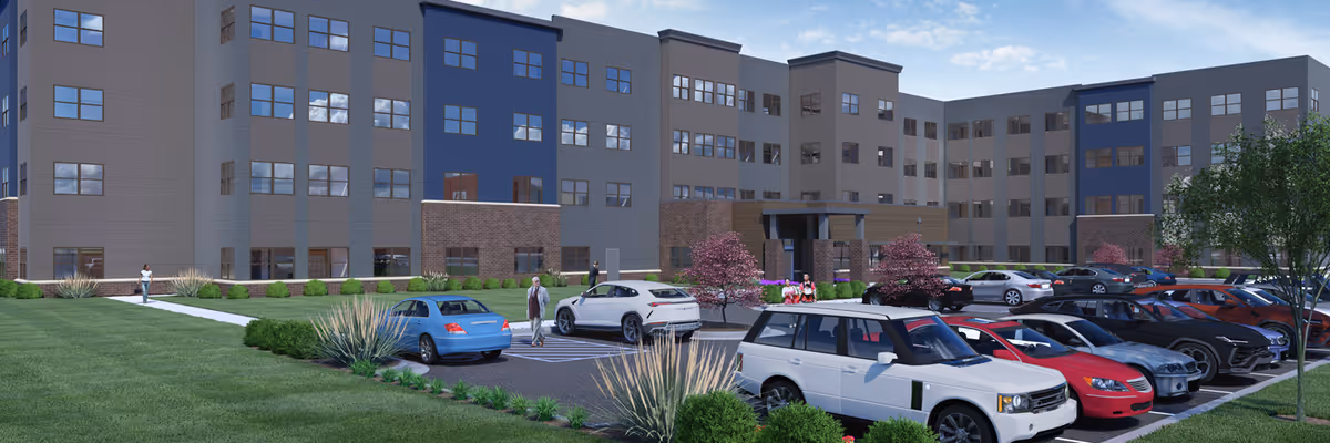 Exterior view of a modern multi-story senior living facility named Sweet Galilee at the Wigwam, showing a large parking lot with several parked cars, landscaped greenery, and a clear blue sky.