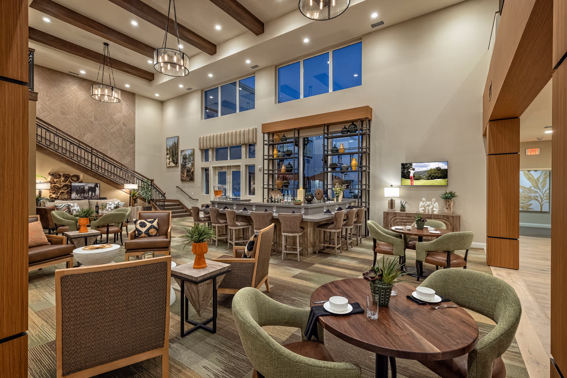 Spacious, well-lit communal lounge and dining area with tables, chairs, a bar, and high ceilings.