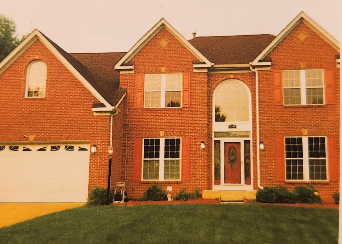 Front view of a brick two-story assisted living building with arched entry and lawn.