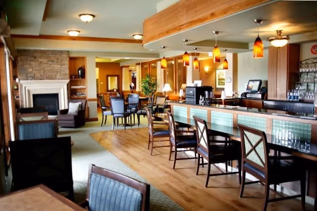 Open dining and lounge area with a long bar, pendant lights, tables, chairs, and a fireplace.